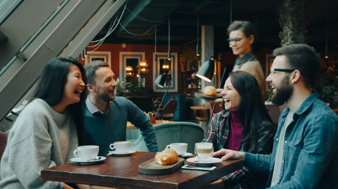 Diverse group of people talking and laughing around a table