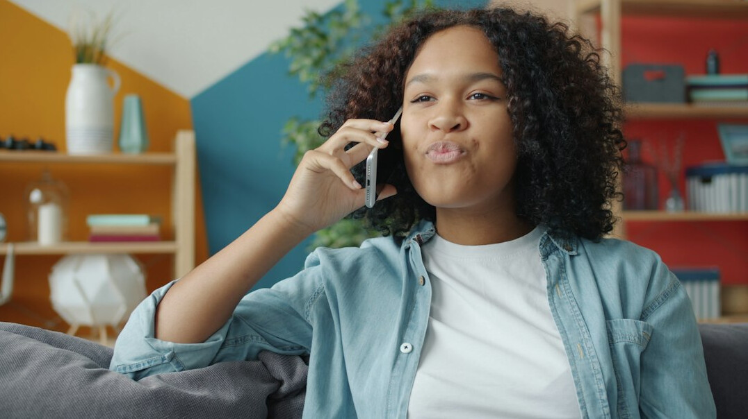 Woman smiling while talking on the phone in a bright living room